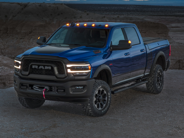 a 2020 blue ram 2500 power wagon at sunset parked next to a cliff with its headlights on