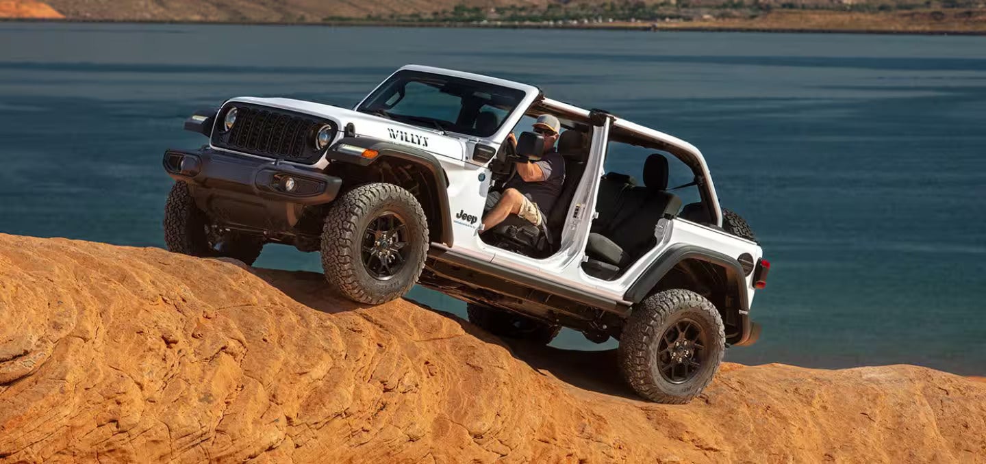 2024 jeep wrangler going over a large rock near a body of water