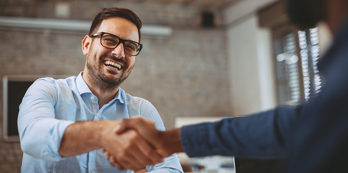 a man shaking hands with another man at a dealership