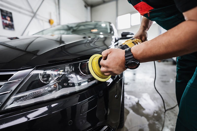 a service technician cleaning the headlights on a vehicle